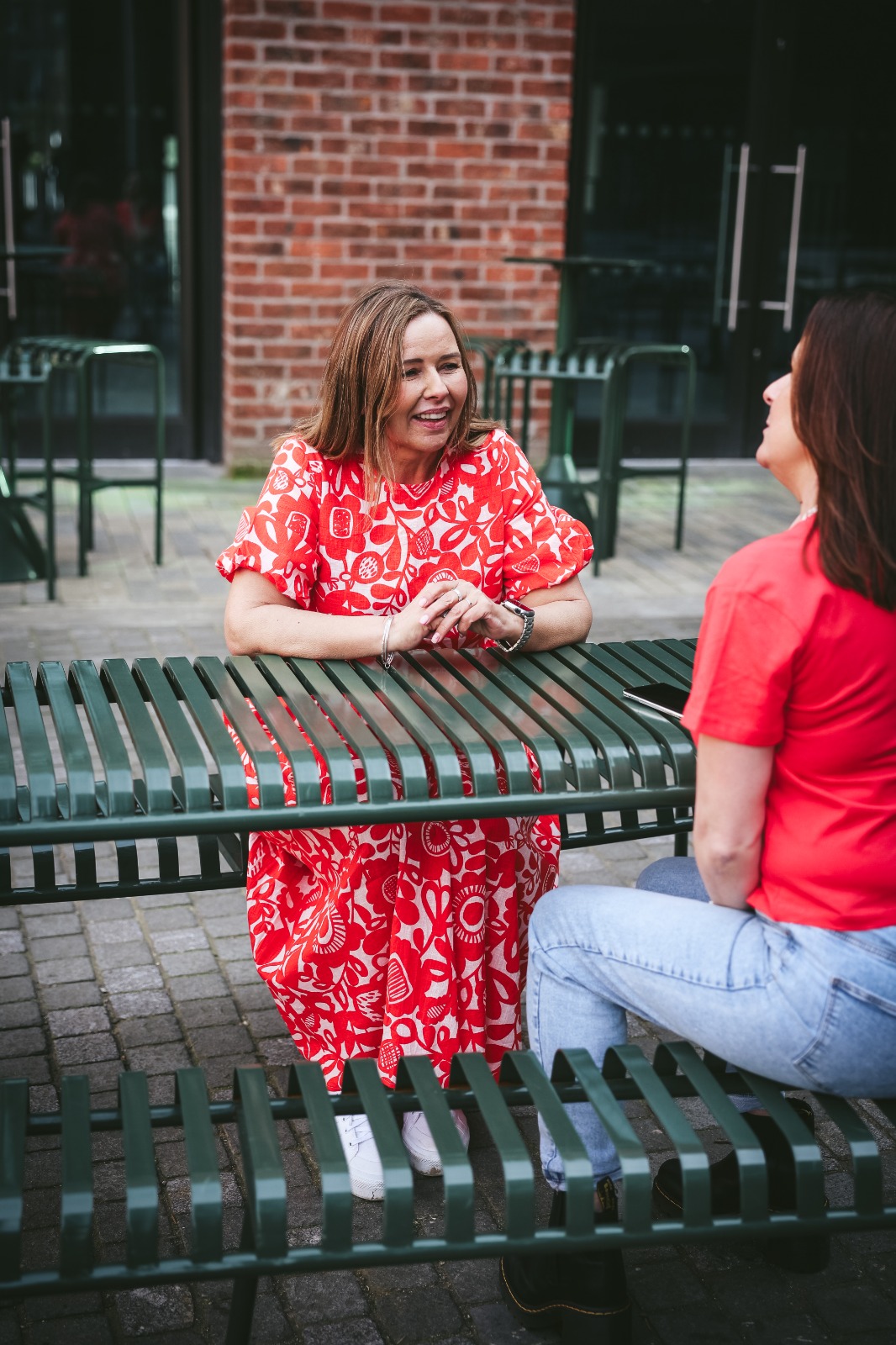 Sharon speaking with another woman at an outdoor table